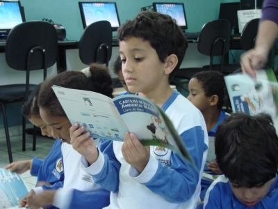 Aluno da escola Martins Fontes lendo o "Livro do Aluno", cartilha de educação ambiental marinha do Projeto Albatroz