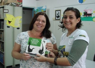 Cynthia Ranieri, assistente de Educação Ambiental do Projeto, entregando cartilha à escola Padre Leonardo Nunes