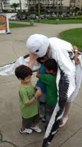 Crianças recebendo abraço de um animador fantasiado de albatroz