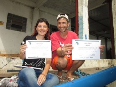 Cassiane Tatsch, estagiária do Projeto Albatroz, entregando certificado de capacitação ao pescador